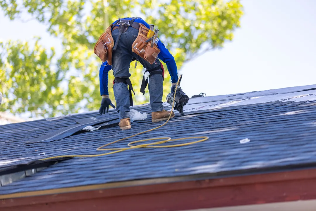 Keller Exteriors crew installing an emergency storm tarp on a Tulsa roof at night